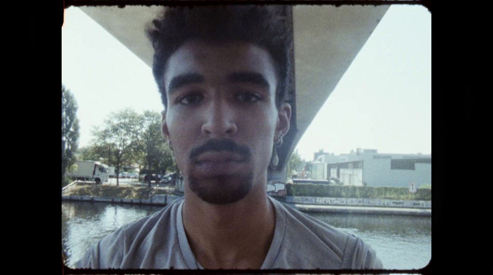 a man with a mustache standing in front of a body of water