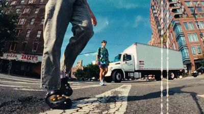 a man riding a skateboard down a street next to tall buildings