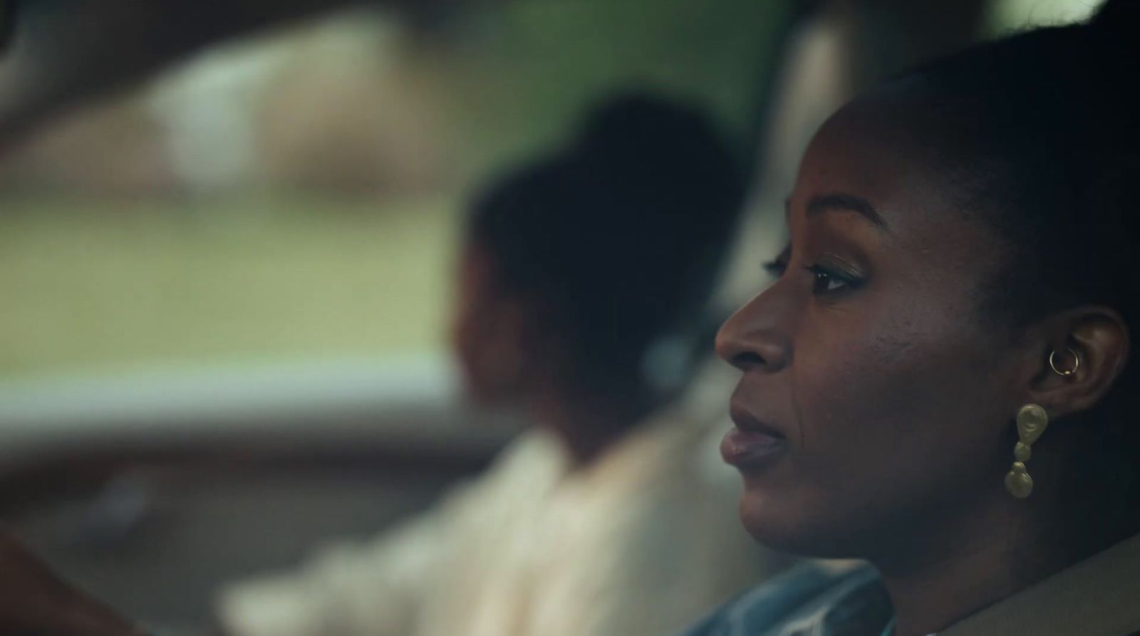 a woman sitting in a car with other people behind her