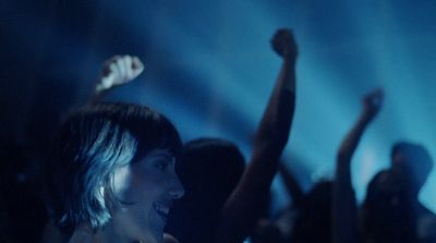 a group of people in a dark room with their arms in the air