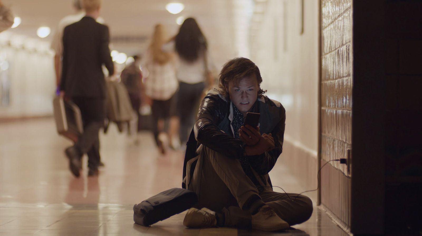 a man sitting on the floor looking at his cell phone