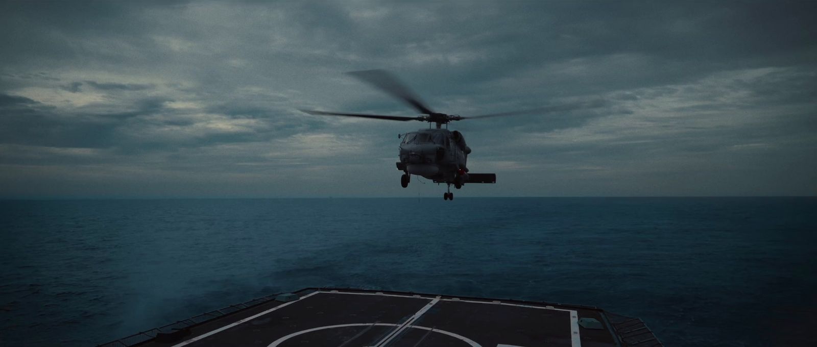 a helicopter flying over the ocean on top of a ship