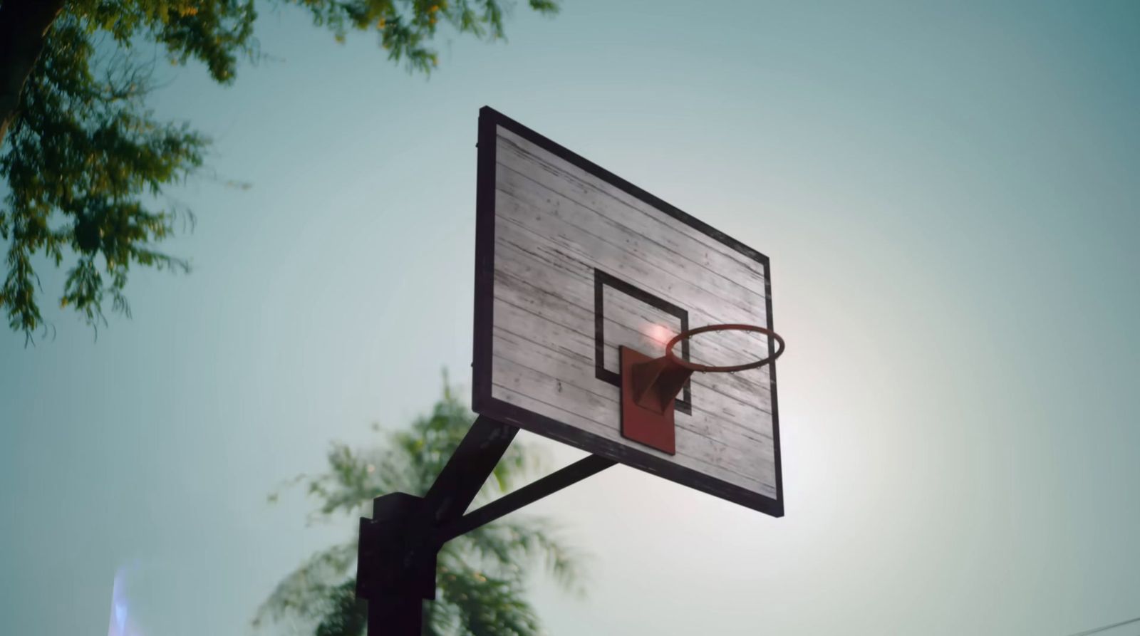 a close up of a basketball hoop with the sun in the background