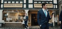 a man in a suit and tie standing in front of a store