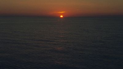 the sun is setting over the ocean on a cloudy day