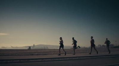 a group of people running across a sandy beach