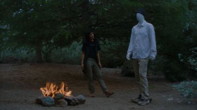 two people standing in front of a campfire