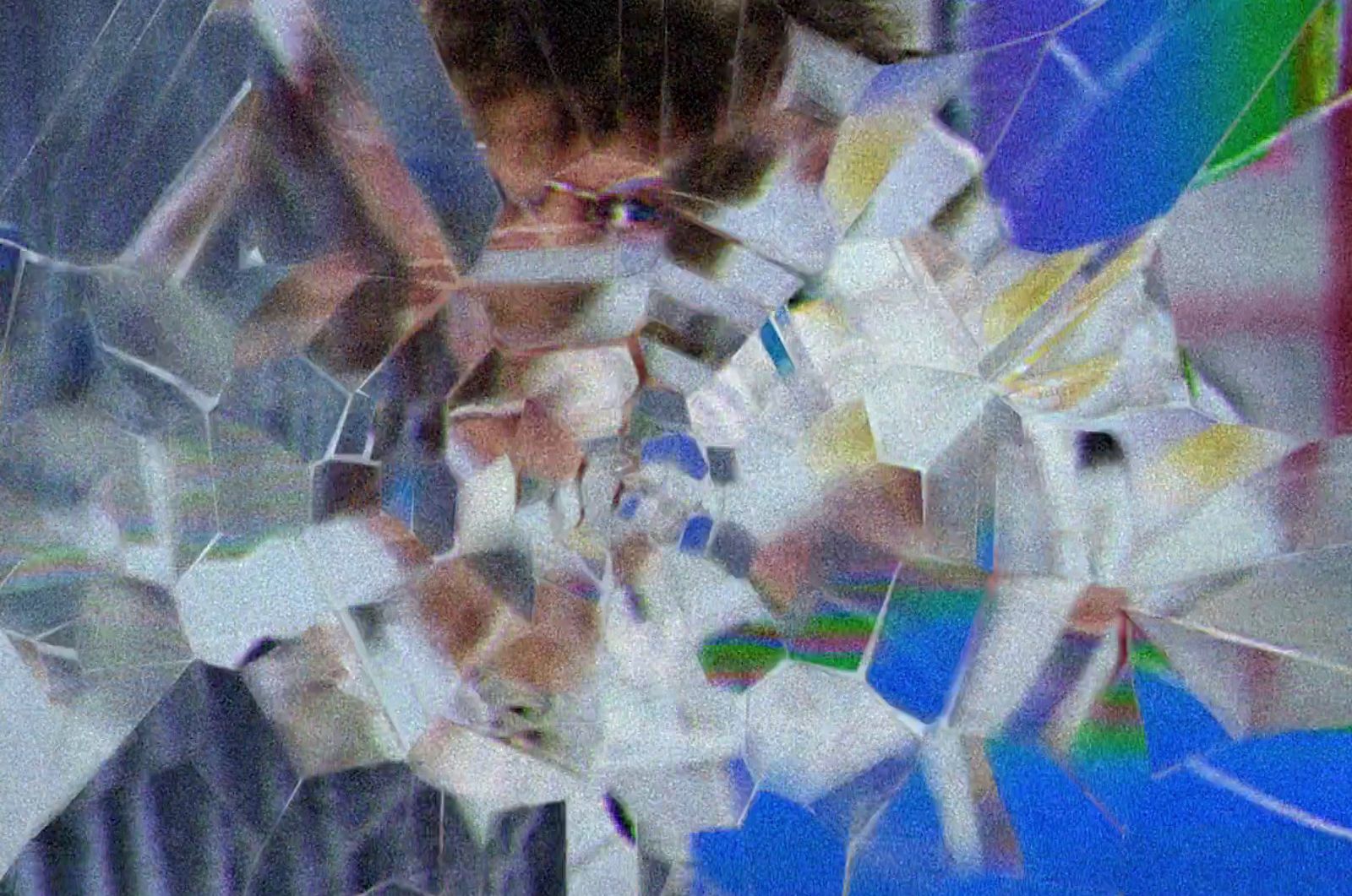 a close up of a person's face through a broken glass window