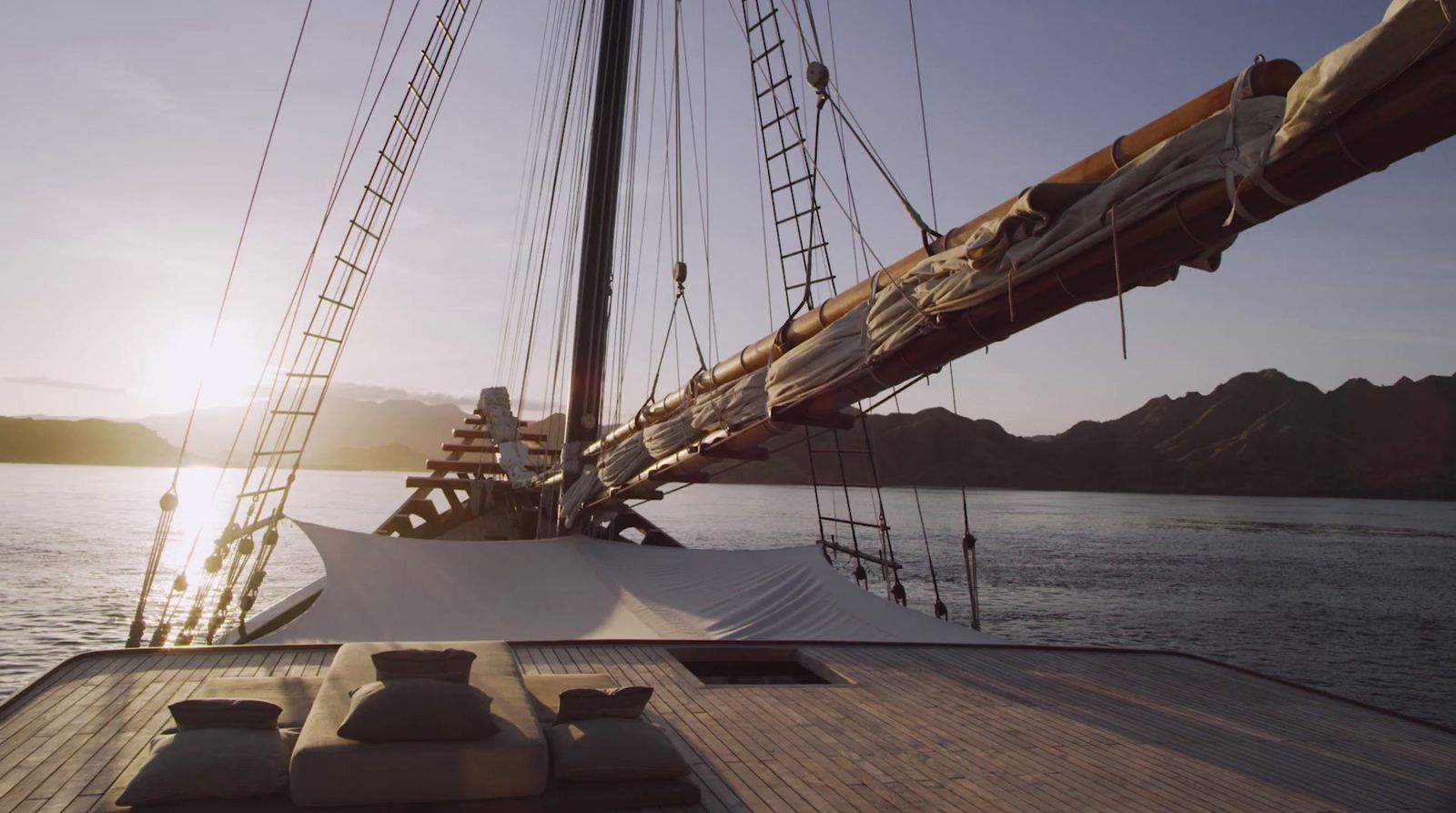 the sun is setting on the deck of a sailboat