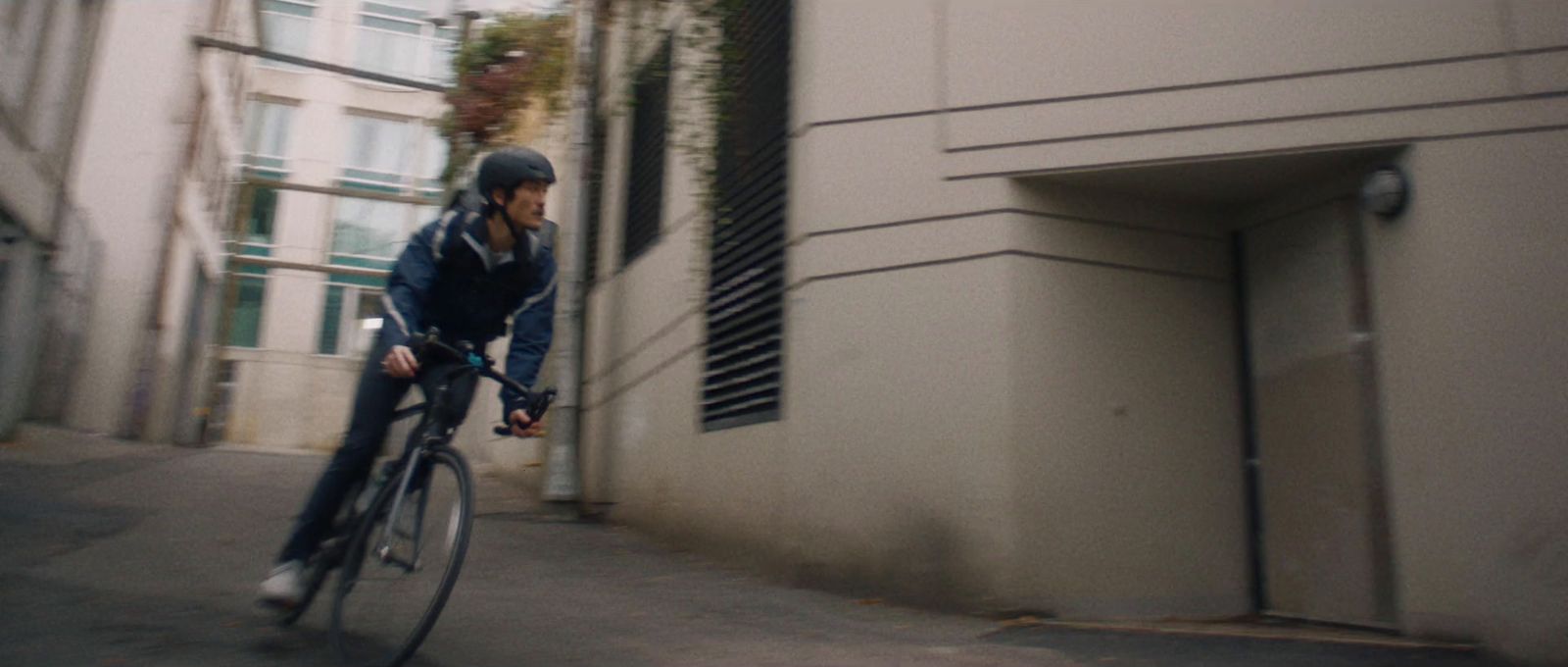 a man riding a bike down a street next to tall buildings