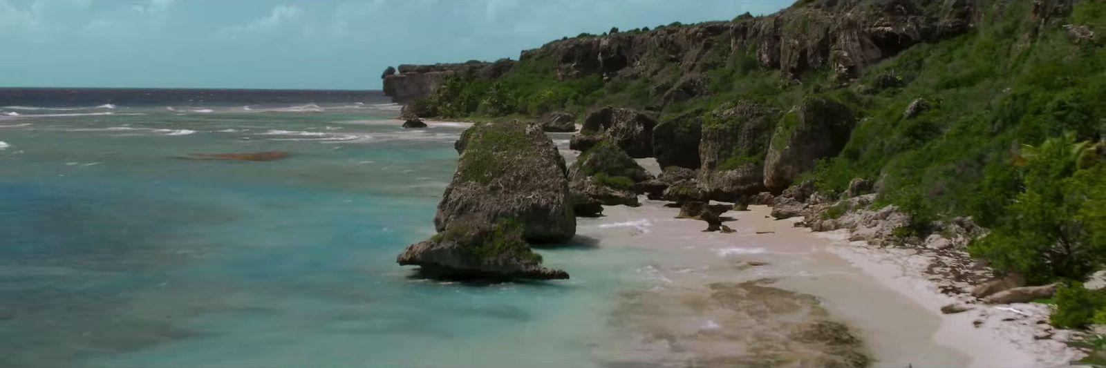 an aerial view of a beach with a cliff in the background