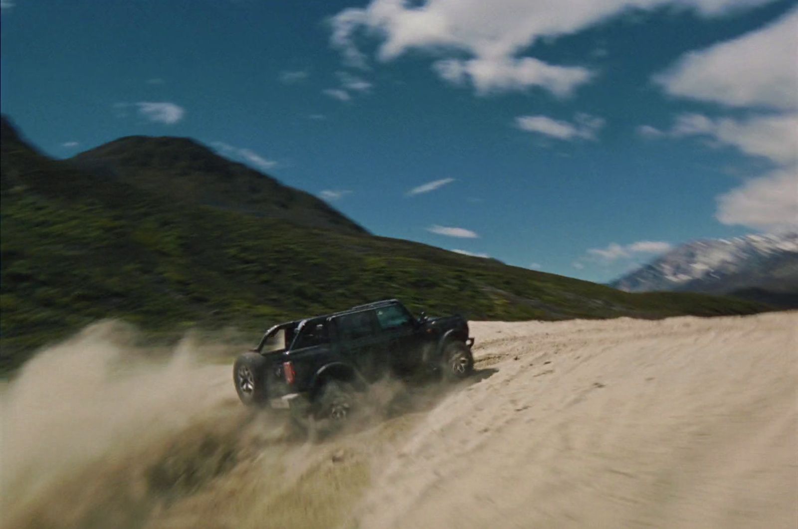 a black truck driving down a dirt road