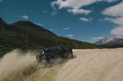 a black truck driving down a dirt road