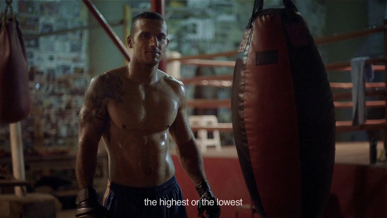 a shirtless man standing next to a punching bag