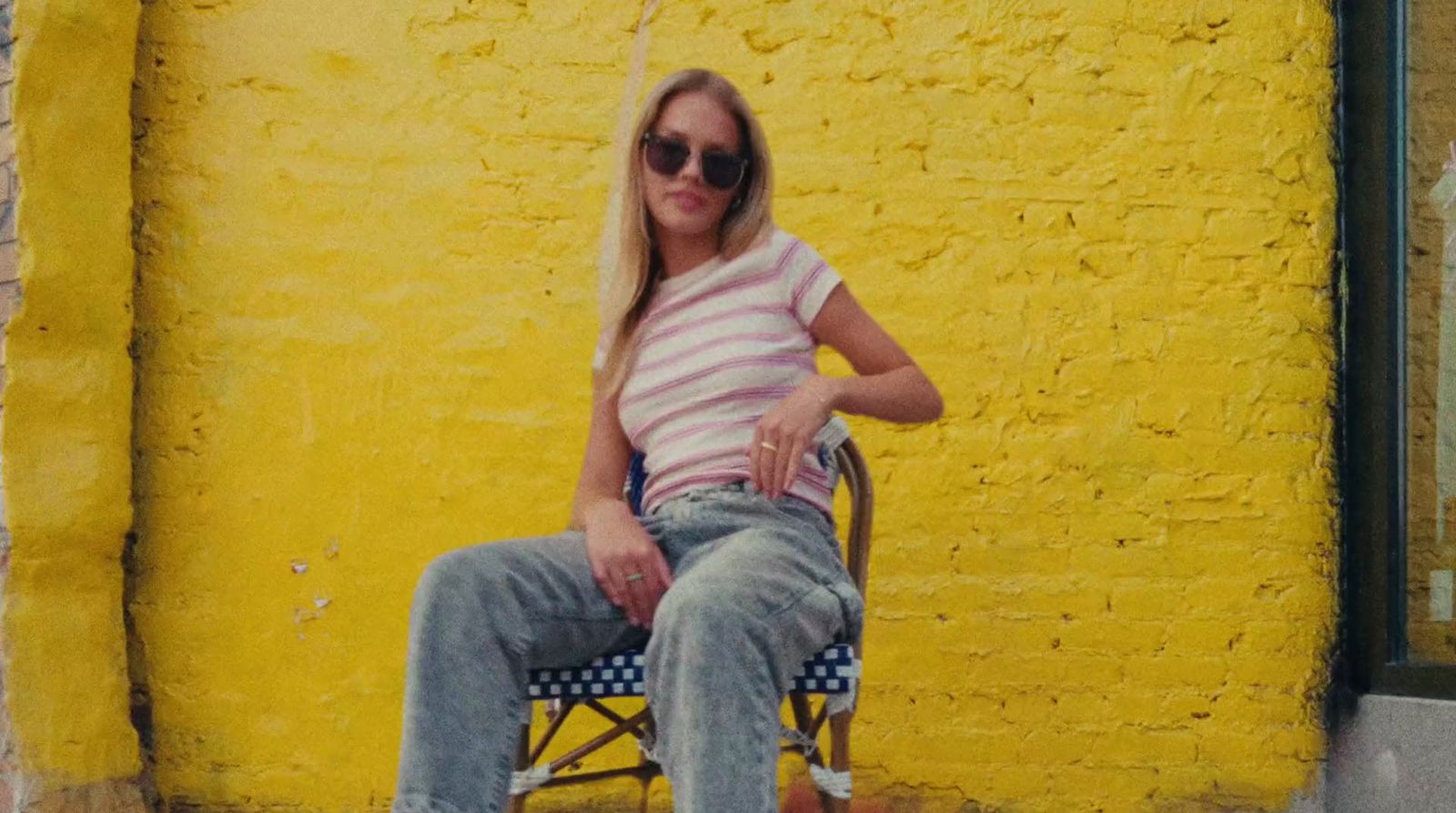 a woman sitting on a chair in front of a yellow wall