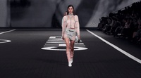 a woman walking down a runway in a short skirt