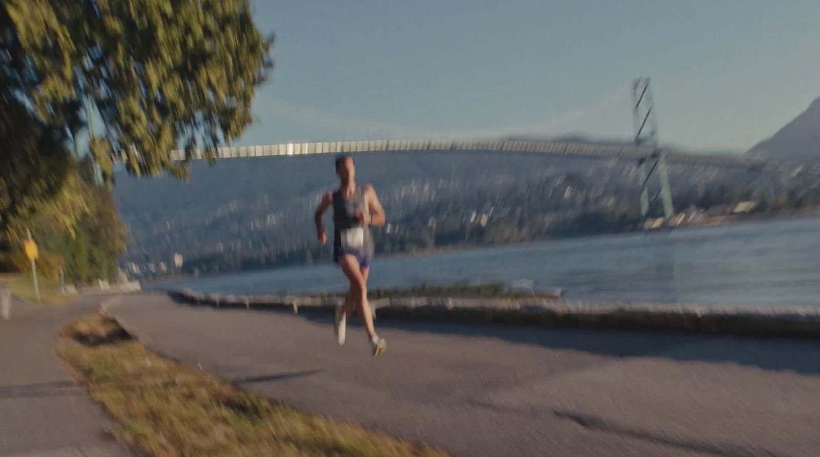 a woman running down a street next to a river