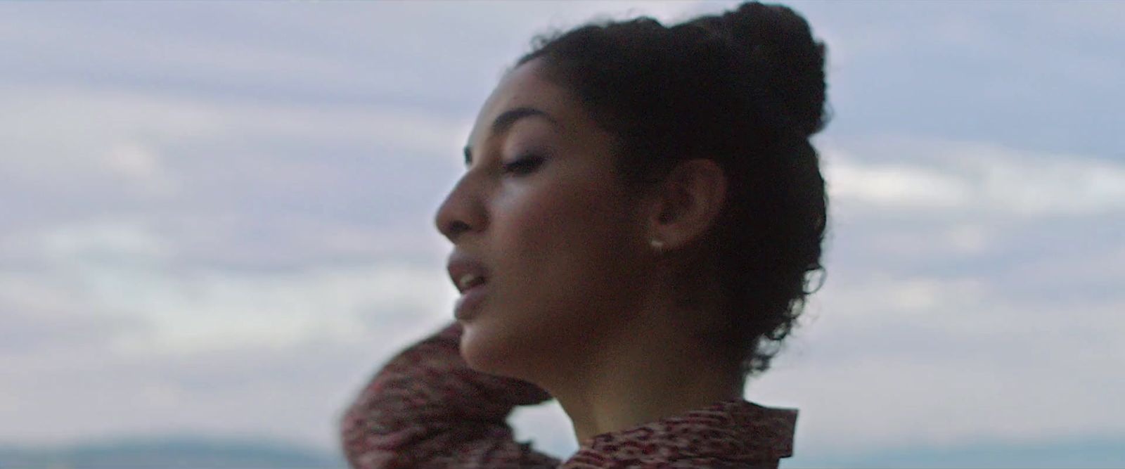 a woman with her hair in a bun looking off into the distance