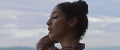 a woman with her hair in a bun looking off into the distance