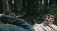 a man laying on the ground in the woods