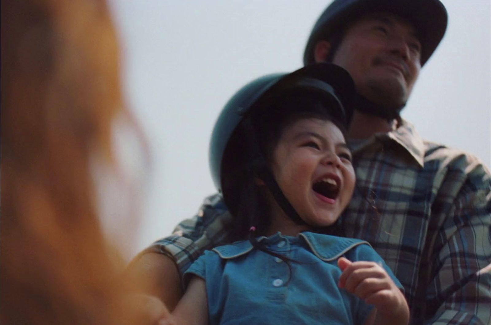 a little girl laughing while standing next to a man