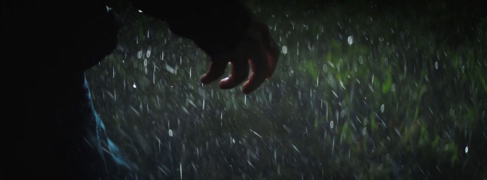 a person standing in the rain with their hand on the ground