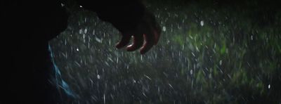 a person standing in the rain with their hand on the ground