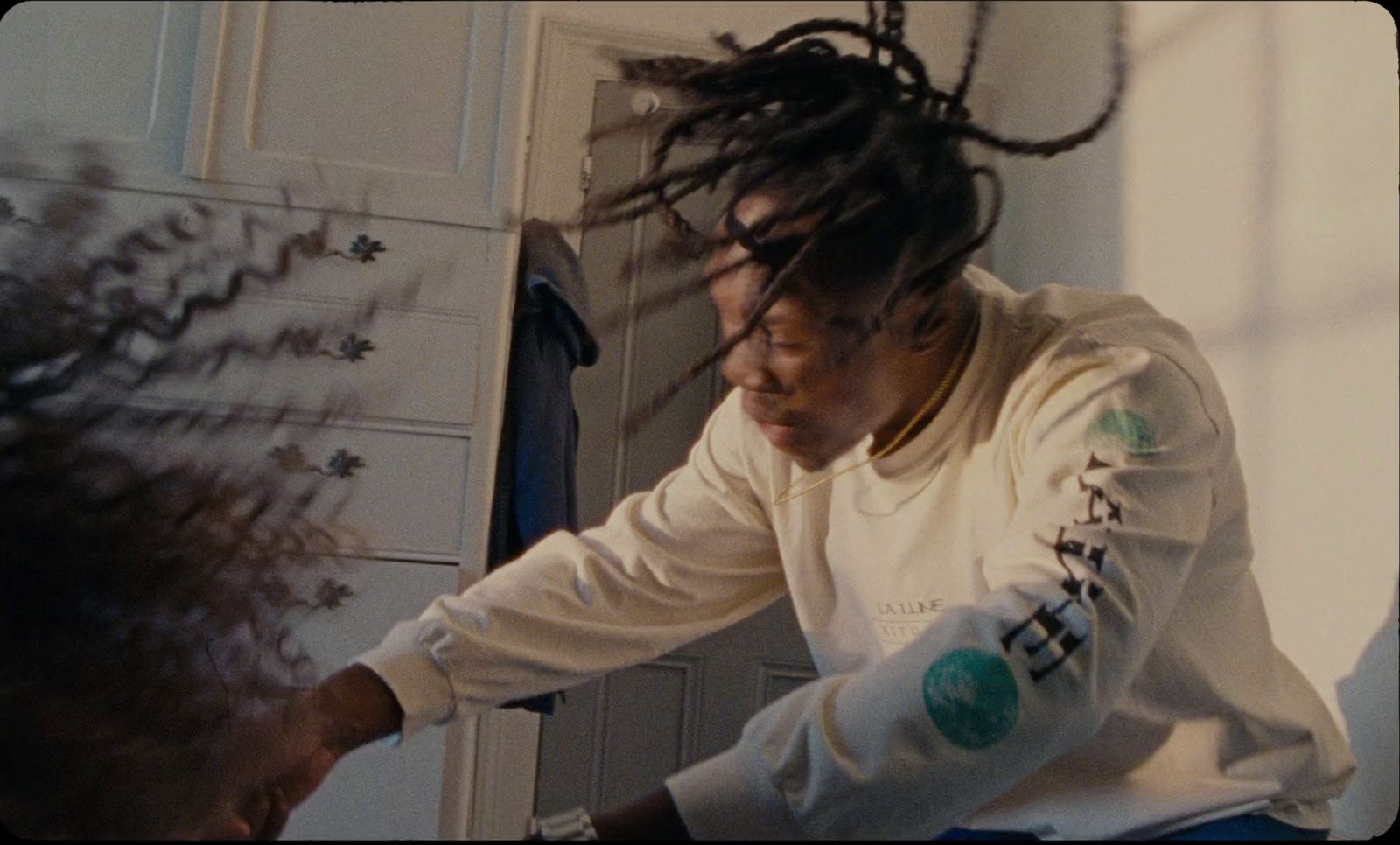 a man with dreadlocks sitting in front of a mirror