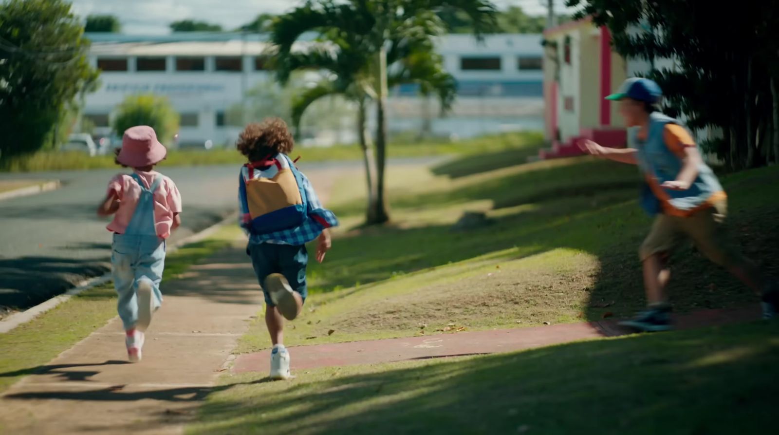 a group of young children running down a sidewalk