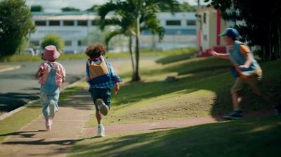 a group of young children running down a sidewalk