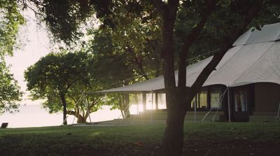 a tent set up in a field next to a body of water