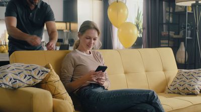 a woman sitting on a couch using a cell phone