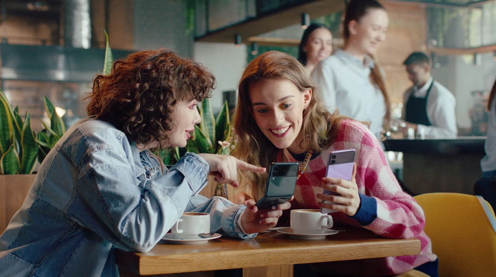 two women sitting at a table looking at a cell phone