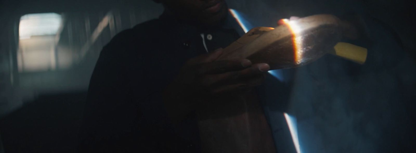 a man holding a wooden object in a dark room