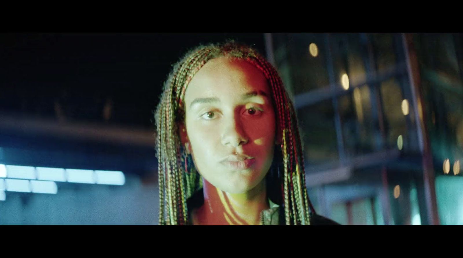 a woman with dreadlocks standing in front of a building