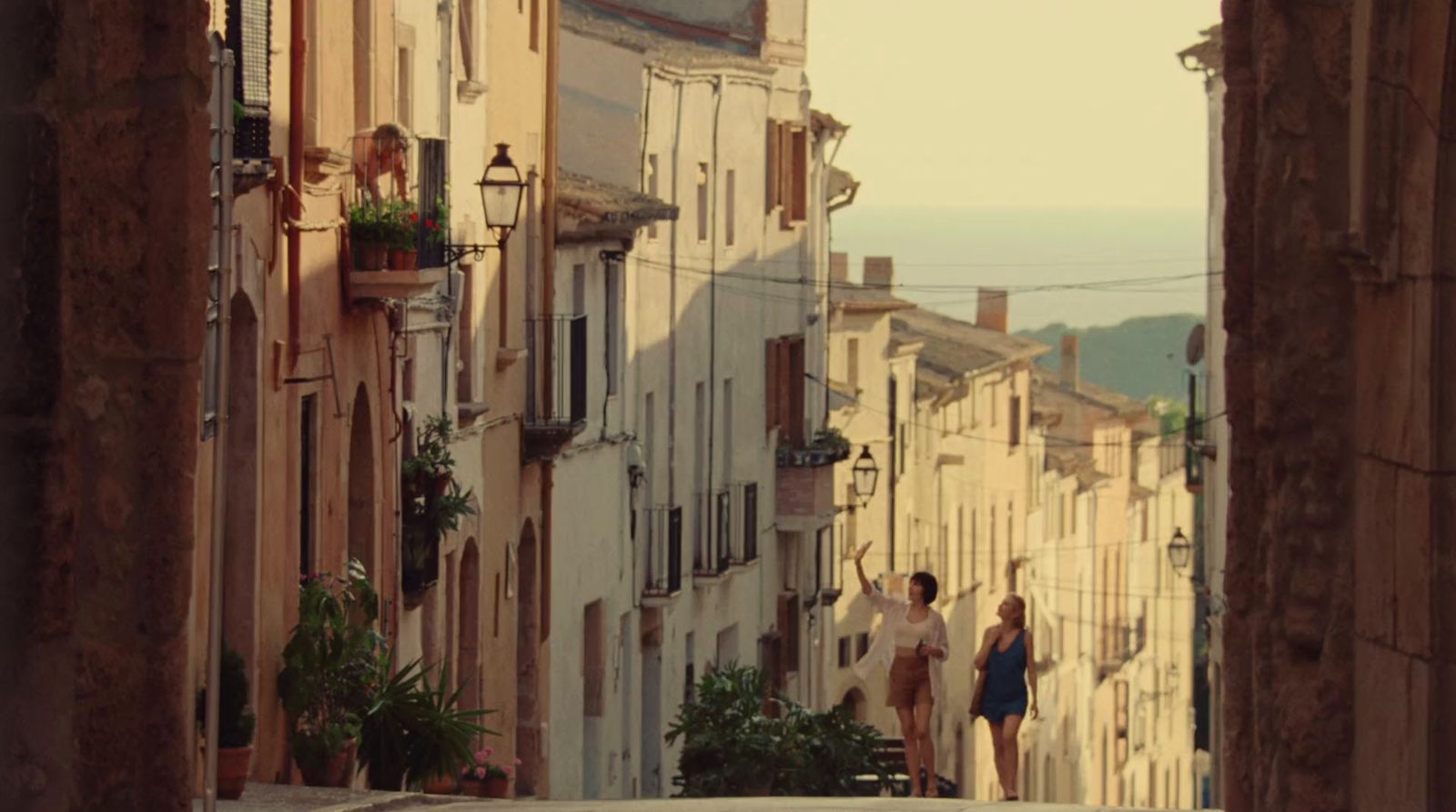 a couple of people walking down a street next to tall buildings