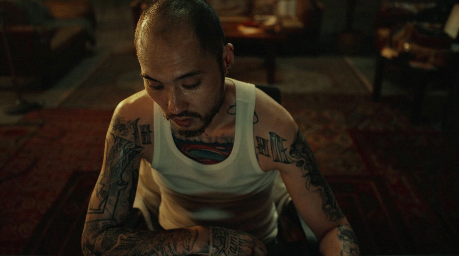 a man with tattoos sitting on a rug