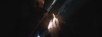 a man holding a violin in the dark