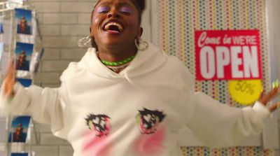 a woman in a white hoodie holding a rack of cds