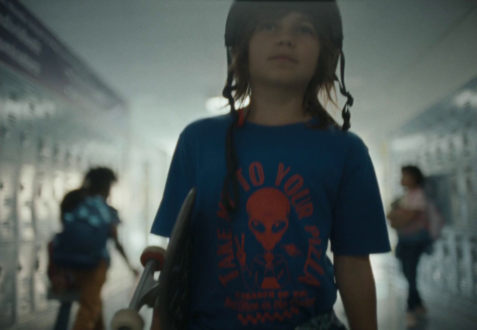 a young girl holding a skateboard in a hallway