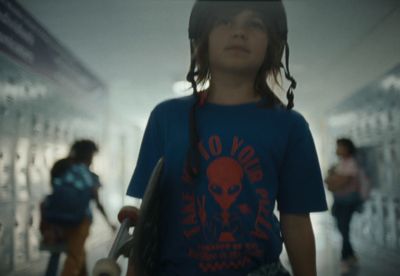 a young girl holding a skateboard in a hallway