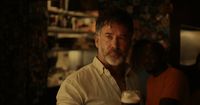 a man holding a glass of beer in a dark room