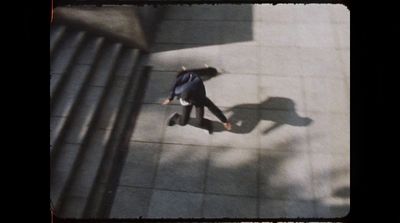 a man walking down a sidewalk next to a metal hand rail