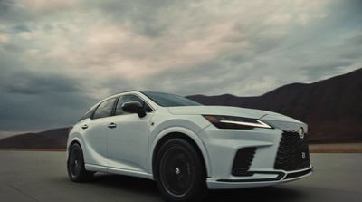 a white car driving down a road under a cloudy sky