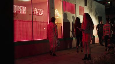 a group of people standing outside of a pizza shop