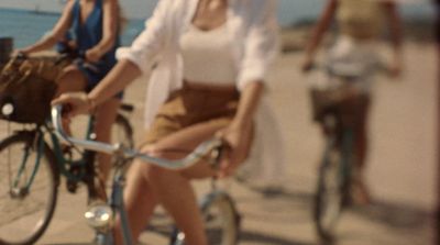 a man riding a bike next to a woman on a beach