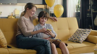 a woman and a boy sitting on a yellow couch