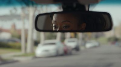 a woman's reflection in the rear view mirror of a car