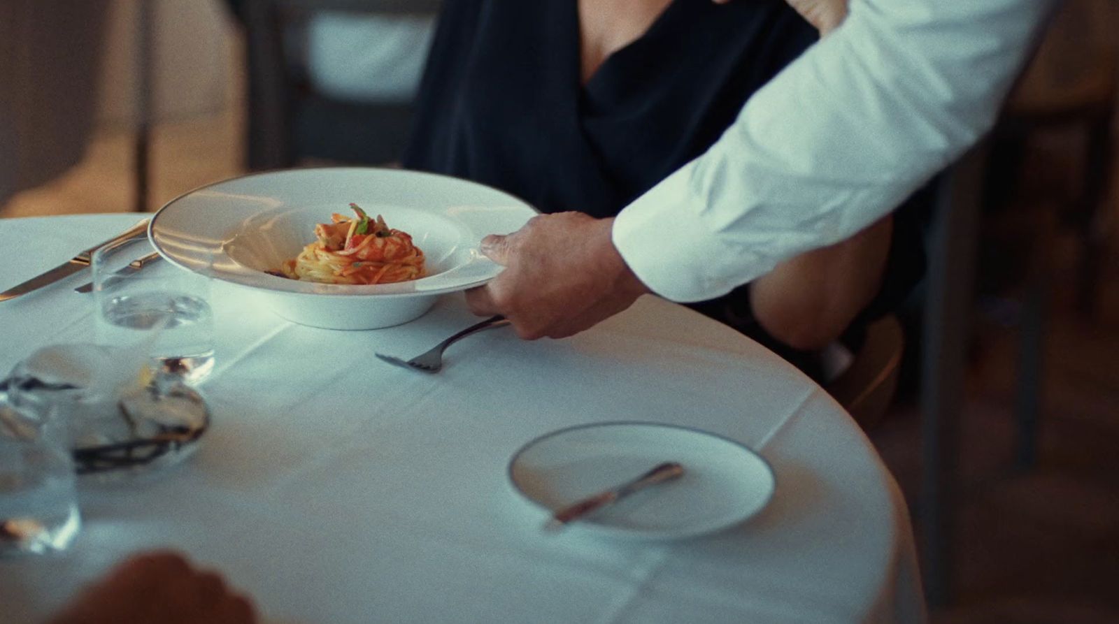 a man and woman sitting at a table with a plate of food