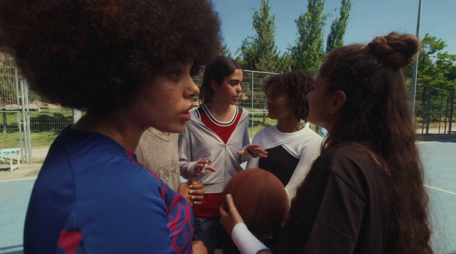 a group of young people standing around a basketball court